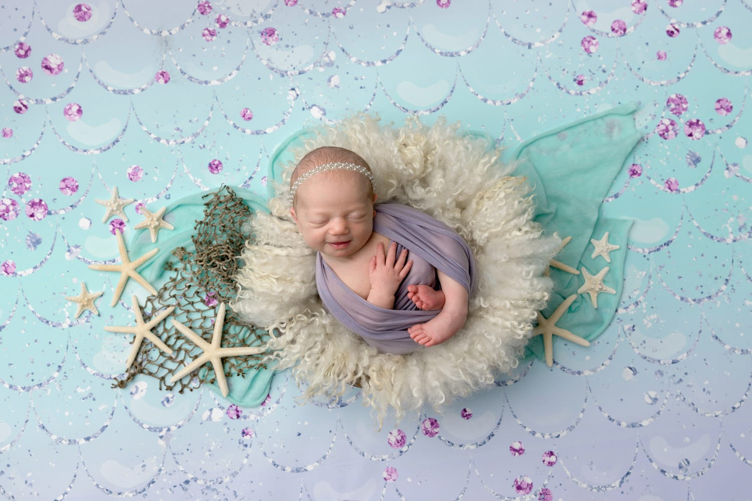 Smiling newborn portrait of a baby girl in a mermaid themed set