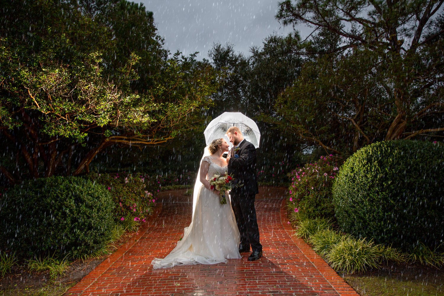 Bride & groom smile at each other under umbrella during their rainy day wedding at Pine Lakes Country Club.
