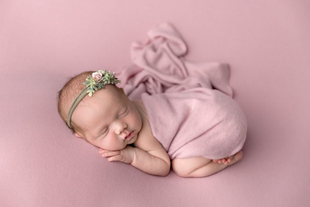Newborn baby girl on a pink background