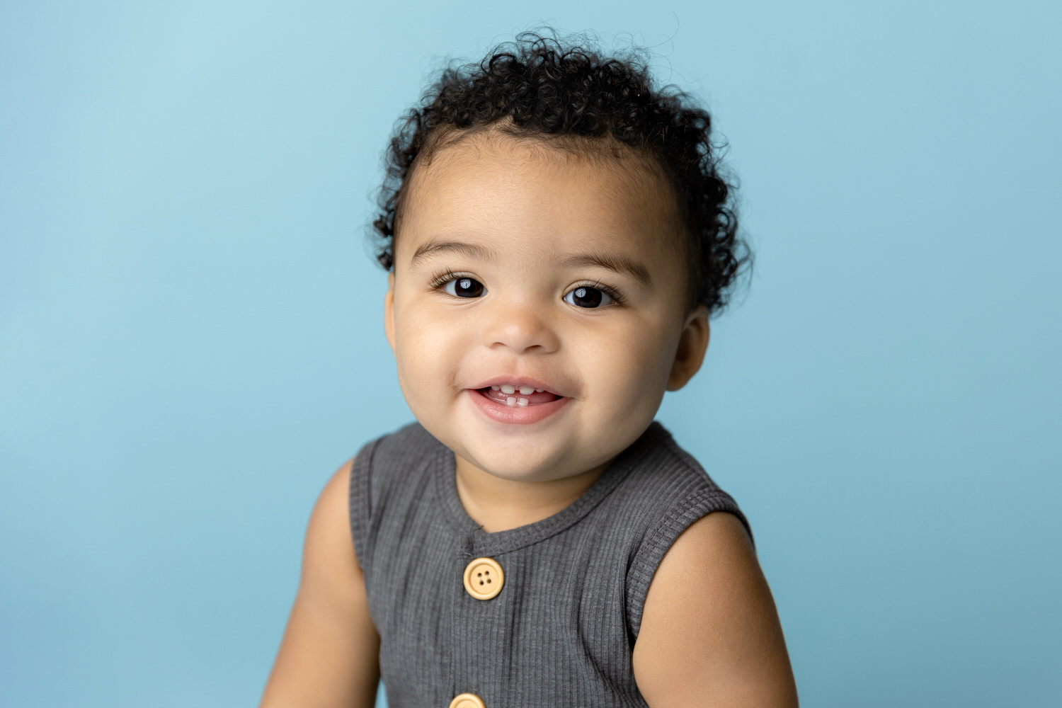 Baby boy smiles for a closeup first birthday portrait on a blue background