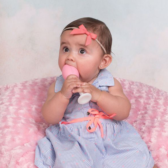 baby holding teething egg with grippie stick attached