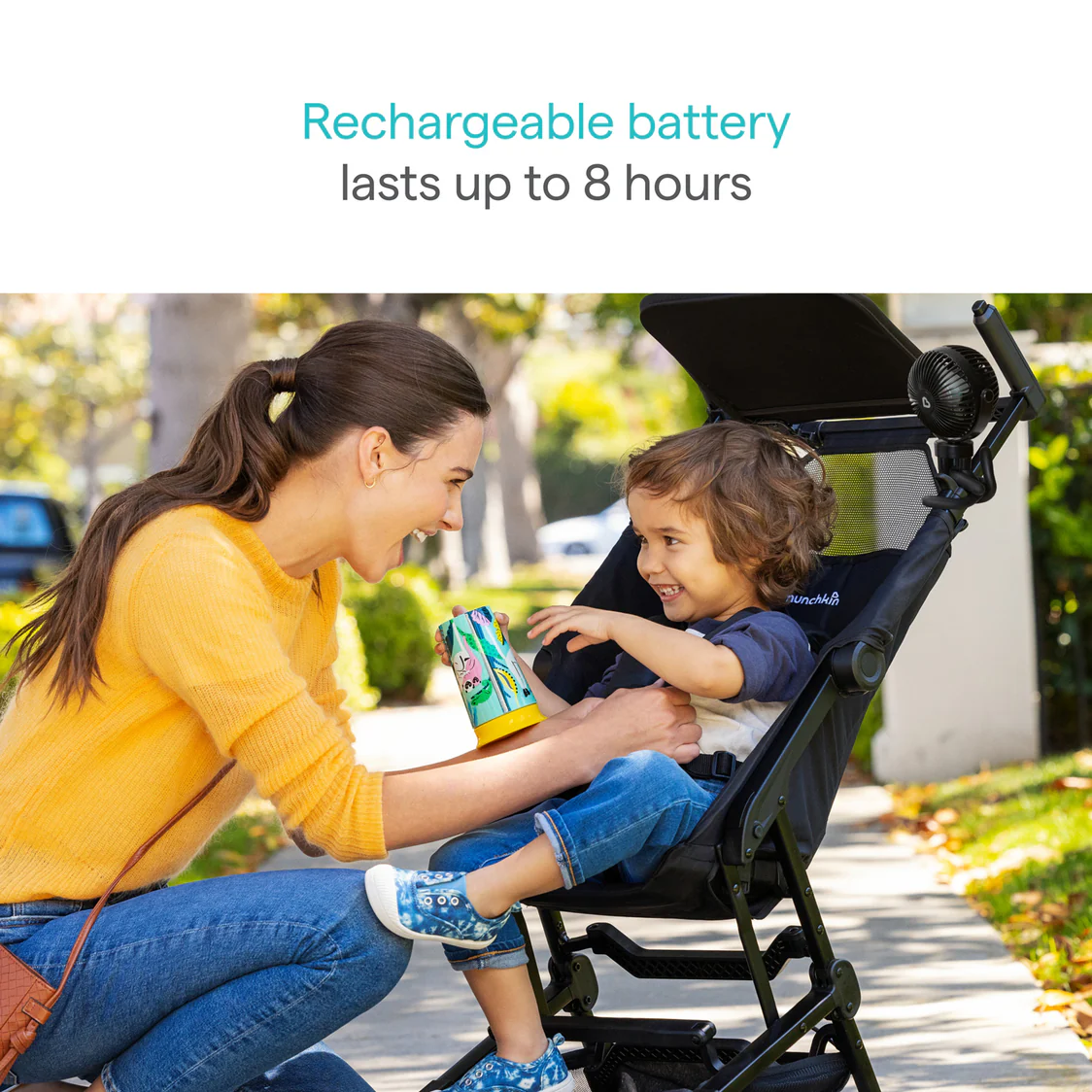 Parent using stroller fan to keep toddler cool in stroller outdoors